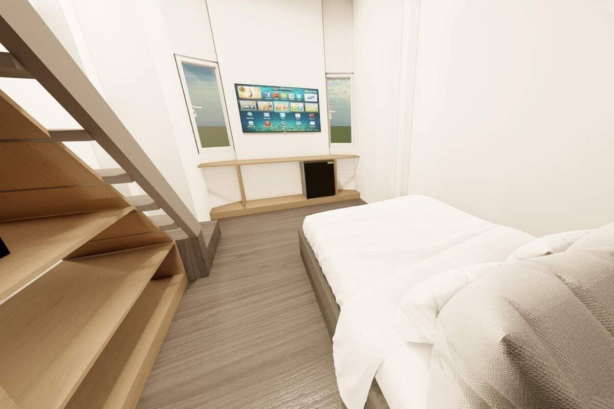 Une chambre d’hôtel moderne équipée d’un lit, d’un escalier en bois et d’un écran numérique affichant des informations sur la chambre.
