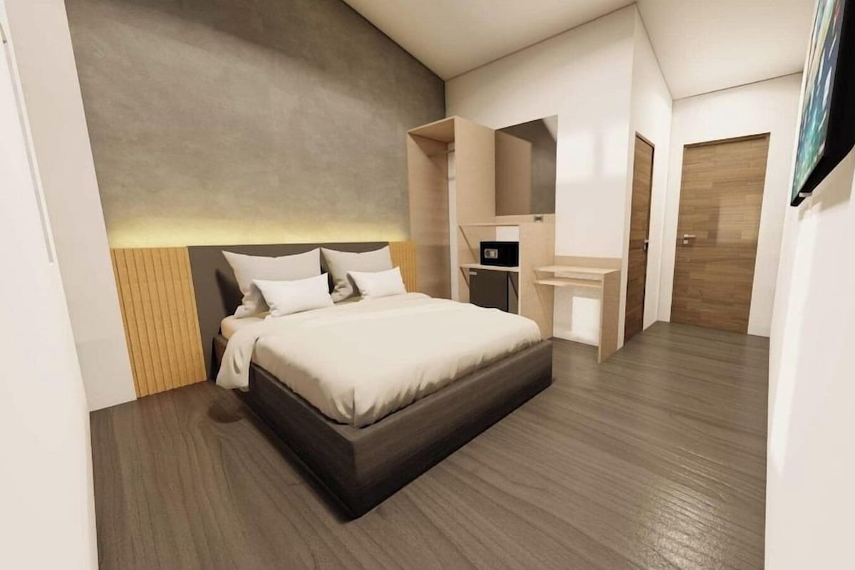 A modern hotel room with a large bed, a desk, and a television.