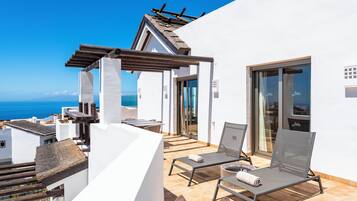 Un balcón con dos sillones de descanso y una pérgola, con vista al litoral.