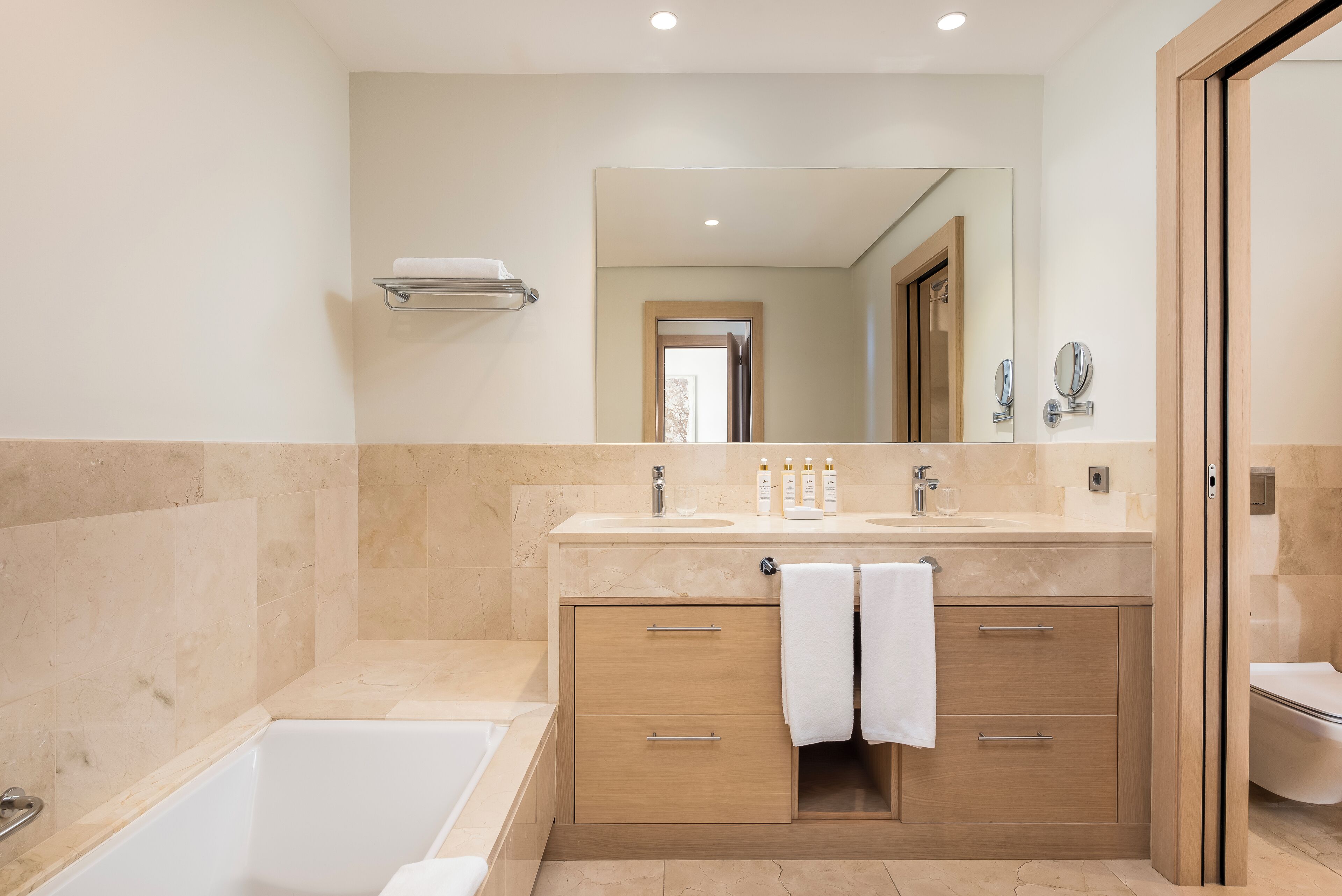 A modern bathroom with a bathtub, a vanity with a mirror, and a toilet.