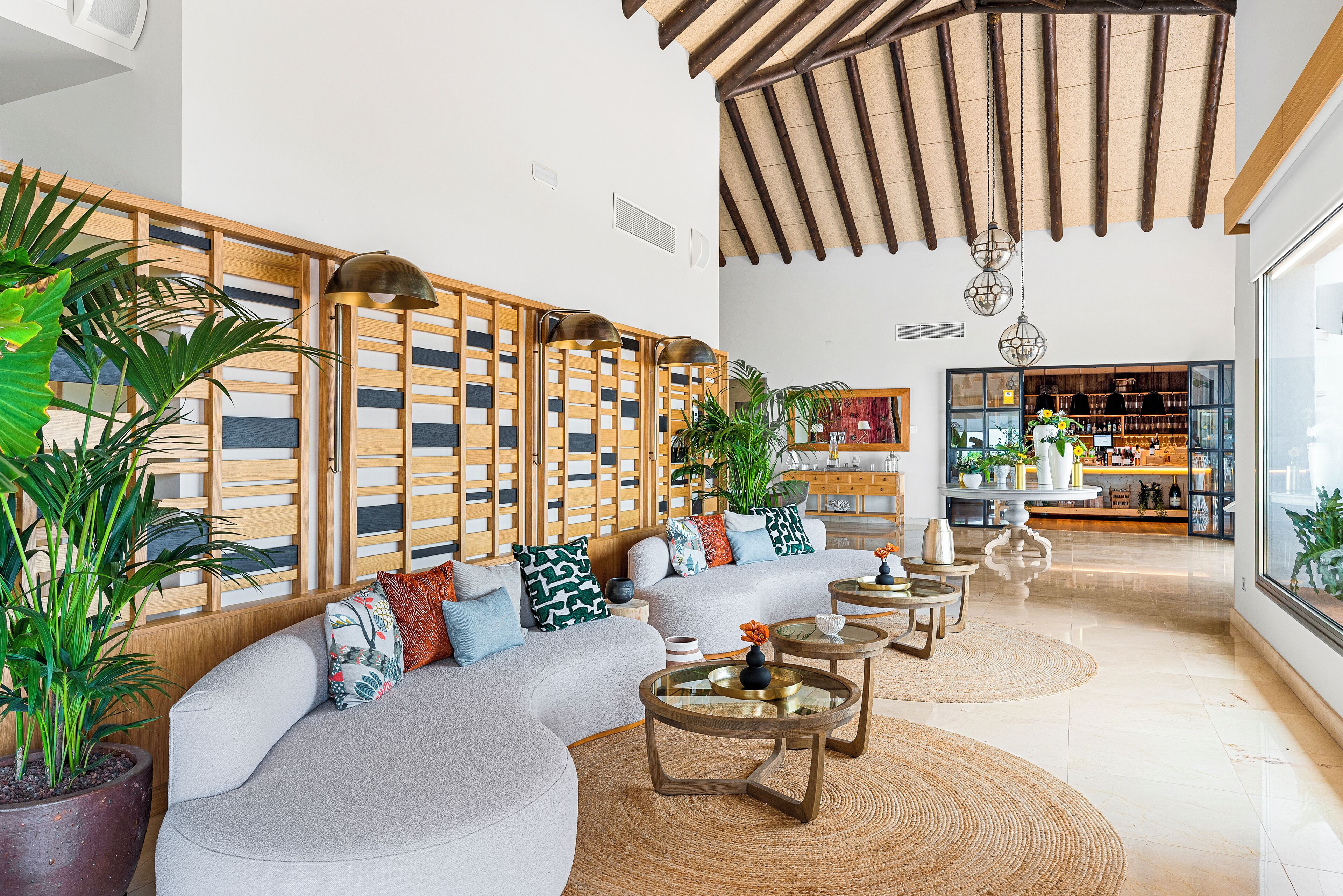 A modern living room with a sectional sofa, round coffee tables, and a wooden partition with vertical slats.