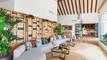 A modern living room with a sectional sofa, round coffee tables, and a wooden partition with vertical slats.