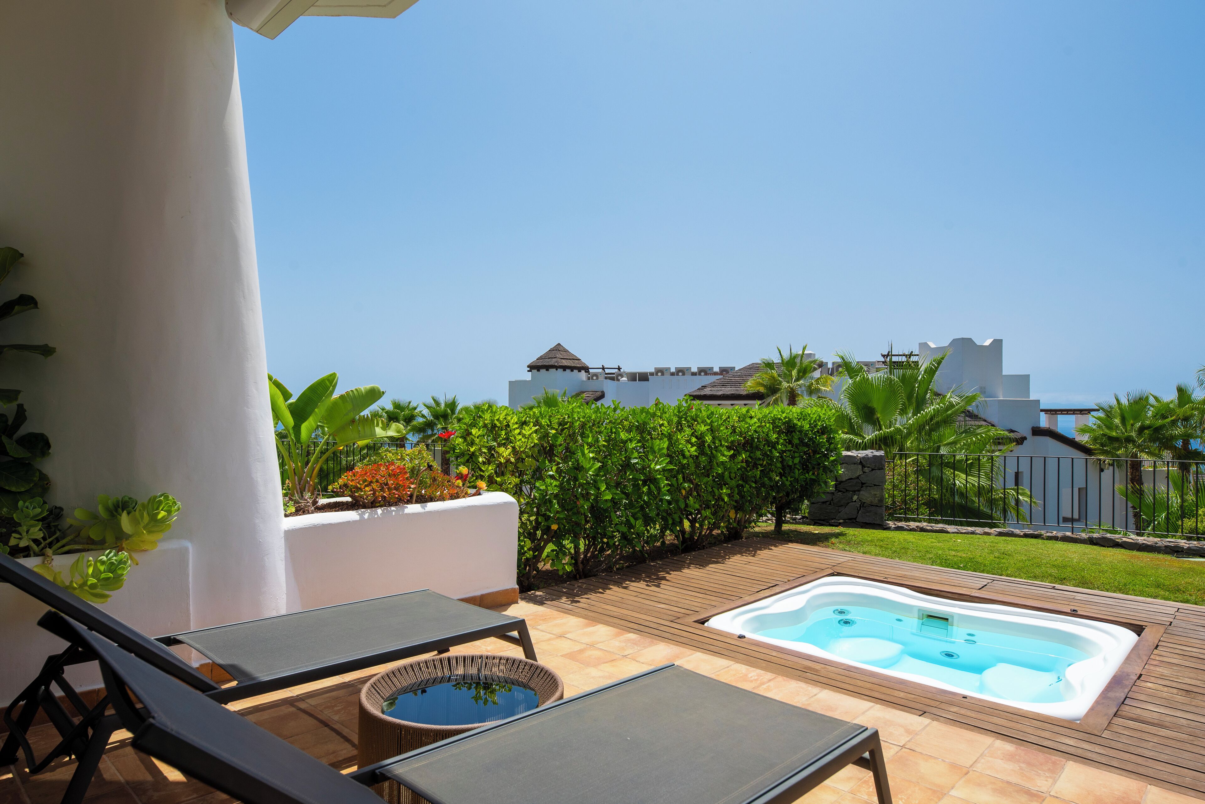 Un patio con sillones de descanso, un jacuzzi y vista al mar.