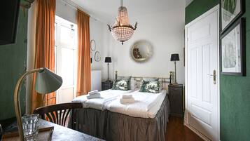 Quarto bem organizado com cama, mesas de cabeceira, escrivaninha e uma cadeira.
