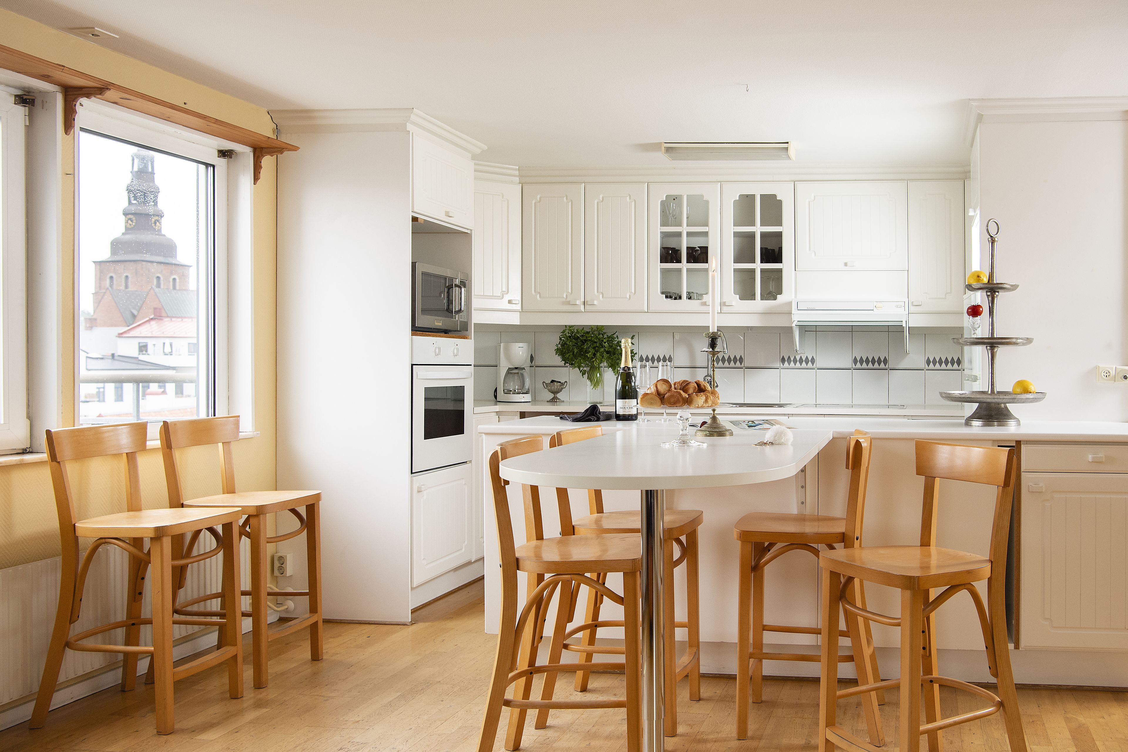 A modern kitchen with white cabinets, a round dining table, and wooden chairs.
