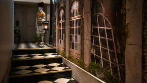 Una escalera con piso a cuadros que conduce a una habitación con ventanas de arco y un mural.