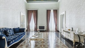 A spacious room with a blue sofa, a glass coffee table, and a white side table with a tray.