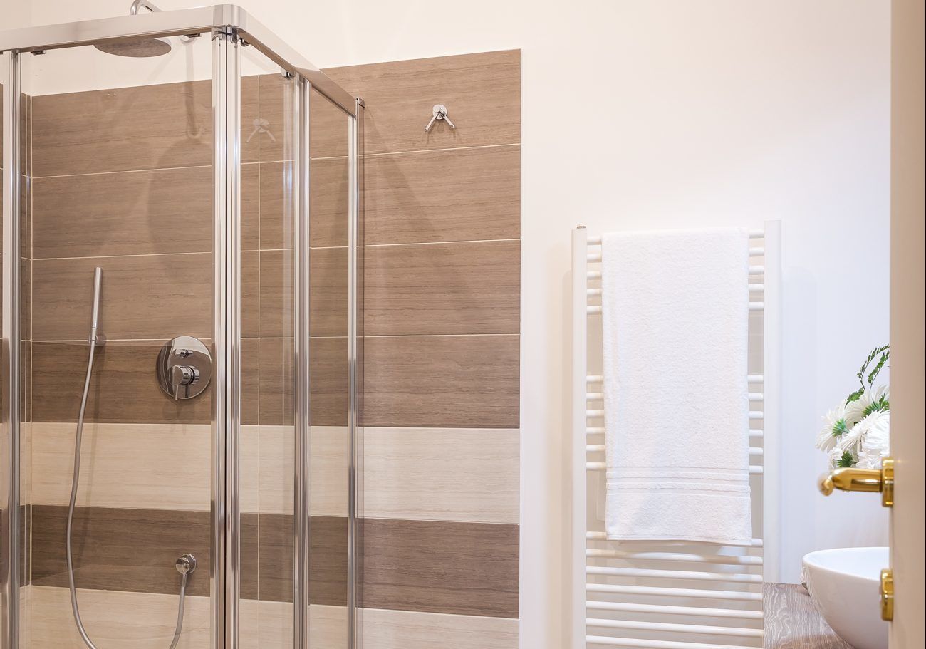 Ein modernes Badezimmer mit einer gläsernen Dusche, einem weißen Waschbecken und einem Handtuchhalter.