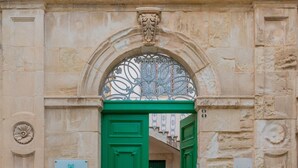 A stone building entrance with a green door and an ornate metal gate.
