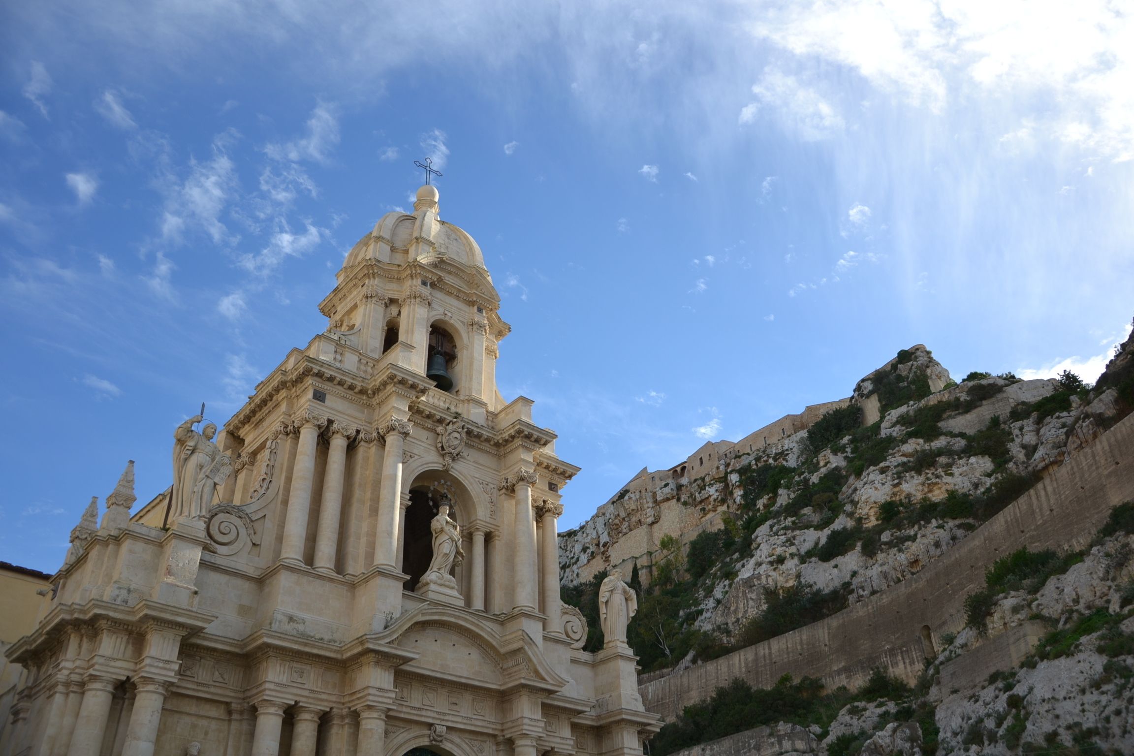 Una iglesia histórica con un campanario, arquitectura clásica y montañas al fondo.