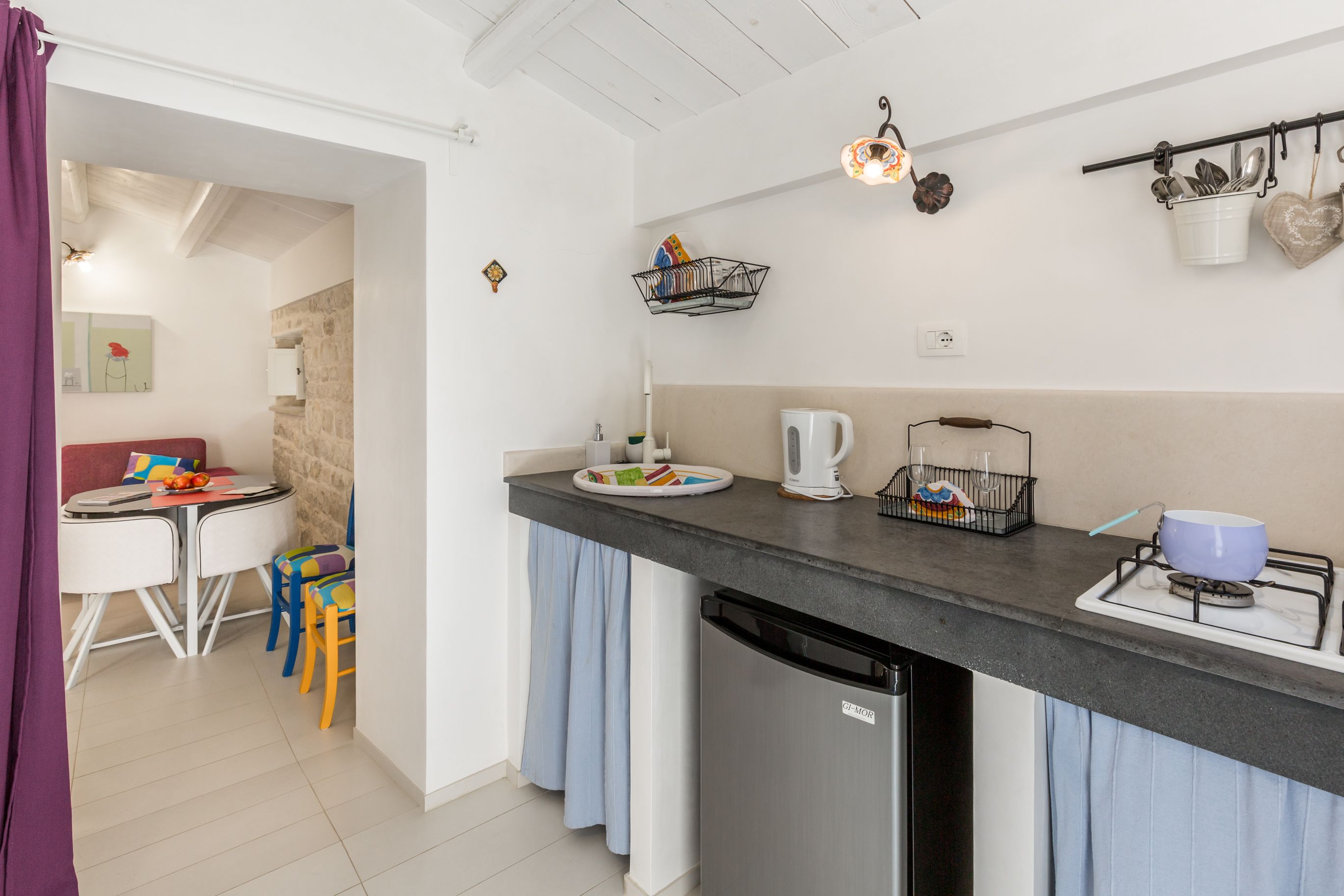 A compact kitchen with a refrigerator, a stove, and a sink. There is a dining area with a table and chairs.