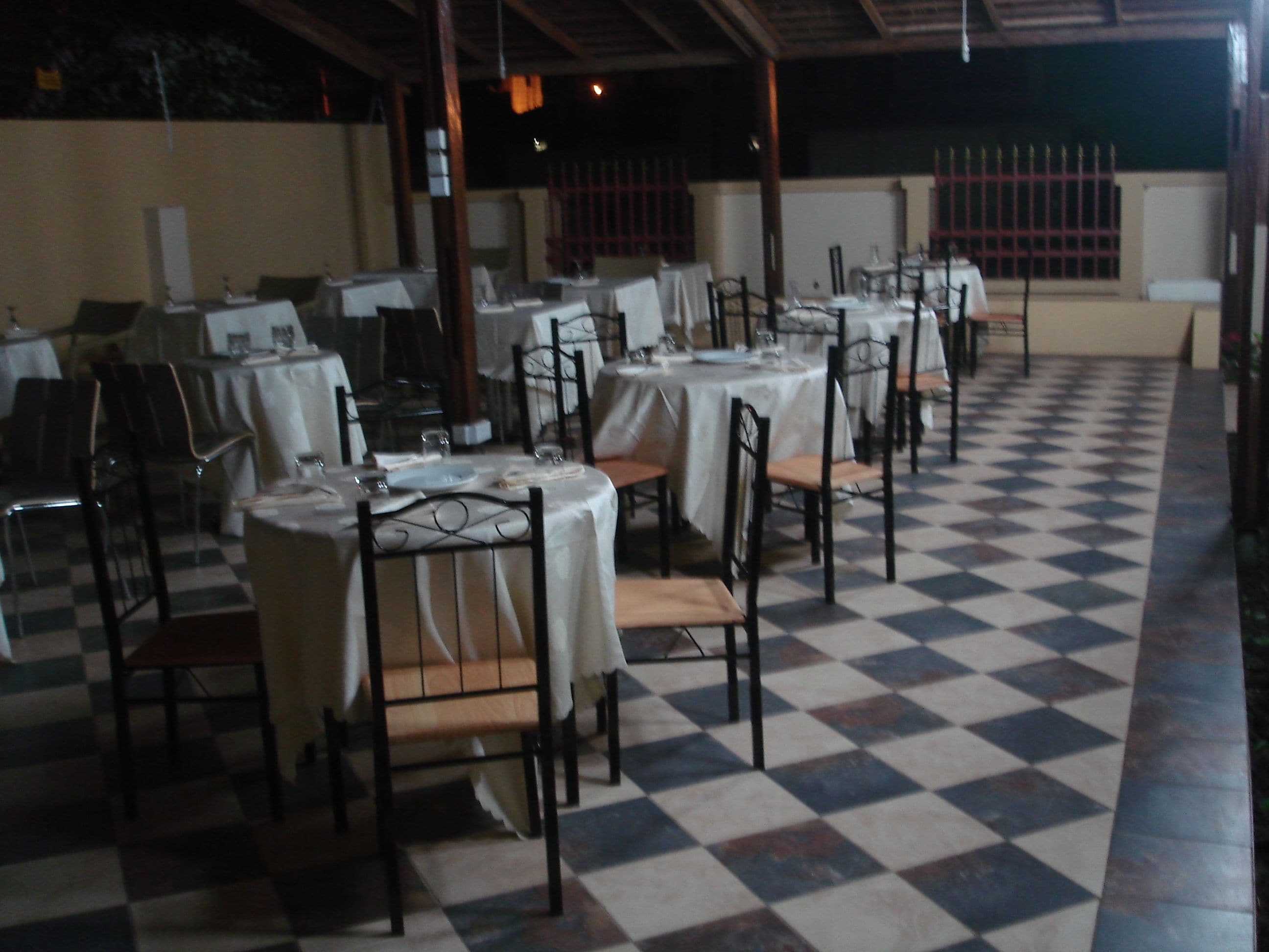 A restaurant with multiple round tables covered with white tablecloths, arranged in rows.