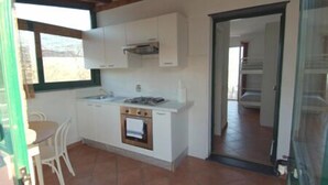 A compact kitchen with white cabinets, a stove, and a window. - Agriturismo l'Ulivo e il Mare (Moneglia)