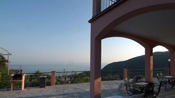 A covered outdoor seating area with a view of the sea and hills. - Agriturismo l'Ulivo e il Mare (Moneglia)