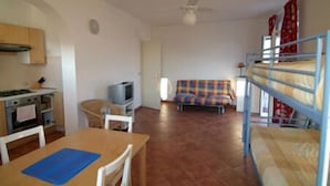 A compact room with a kitchenette, a dining area, a sofa, and a bunk bed. - Agriturismo l'Ulivo e il Mare (Moneglia)