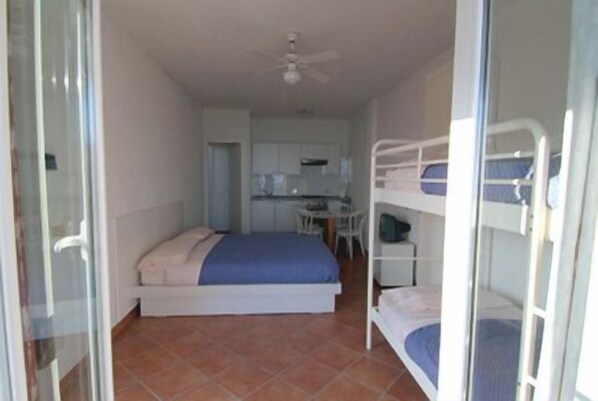 A compact room with a bed, a bunk bed, and a kitchenette area. - Agriturismo l'Ulivo e il Mare (Moneglia)