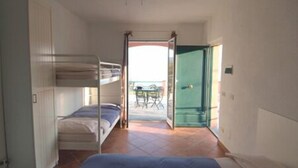 A room with bunk beds, a door leading outside, and a ceiling fan. - Agriturismo l'Ulivo e il Mare (Moneglia)