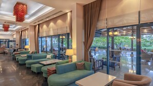 Eine moderne Hotelhalle mit grünen Sofas, einem weißen Tisch und großen Fenstern mit Blick ins Freie.