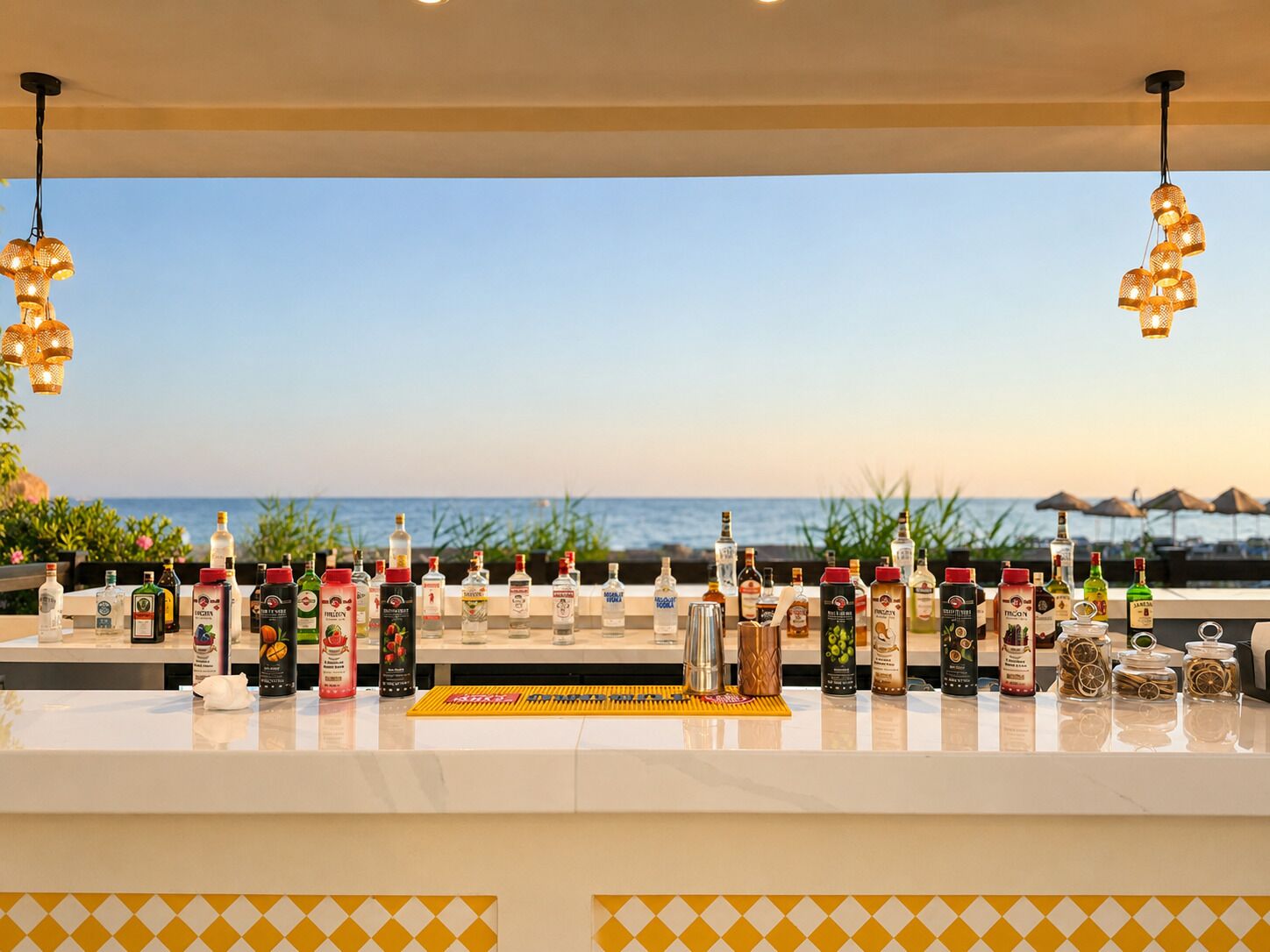 Un bar con vista al océano, botellas de licor y luces colgantes.
