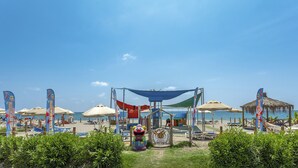 Ein Strand mit Sonnenschirmen, Liegestühlen und einem Spielbereich für Kinder.
