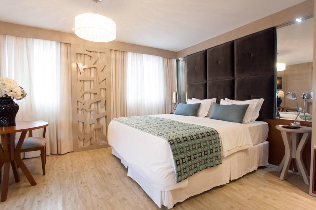 A hotel room with a large bed, a desk, and a chair.
