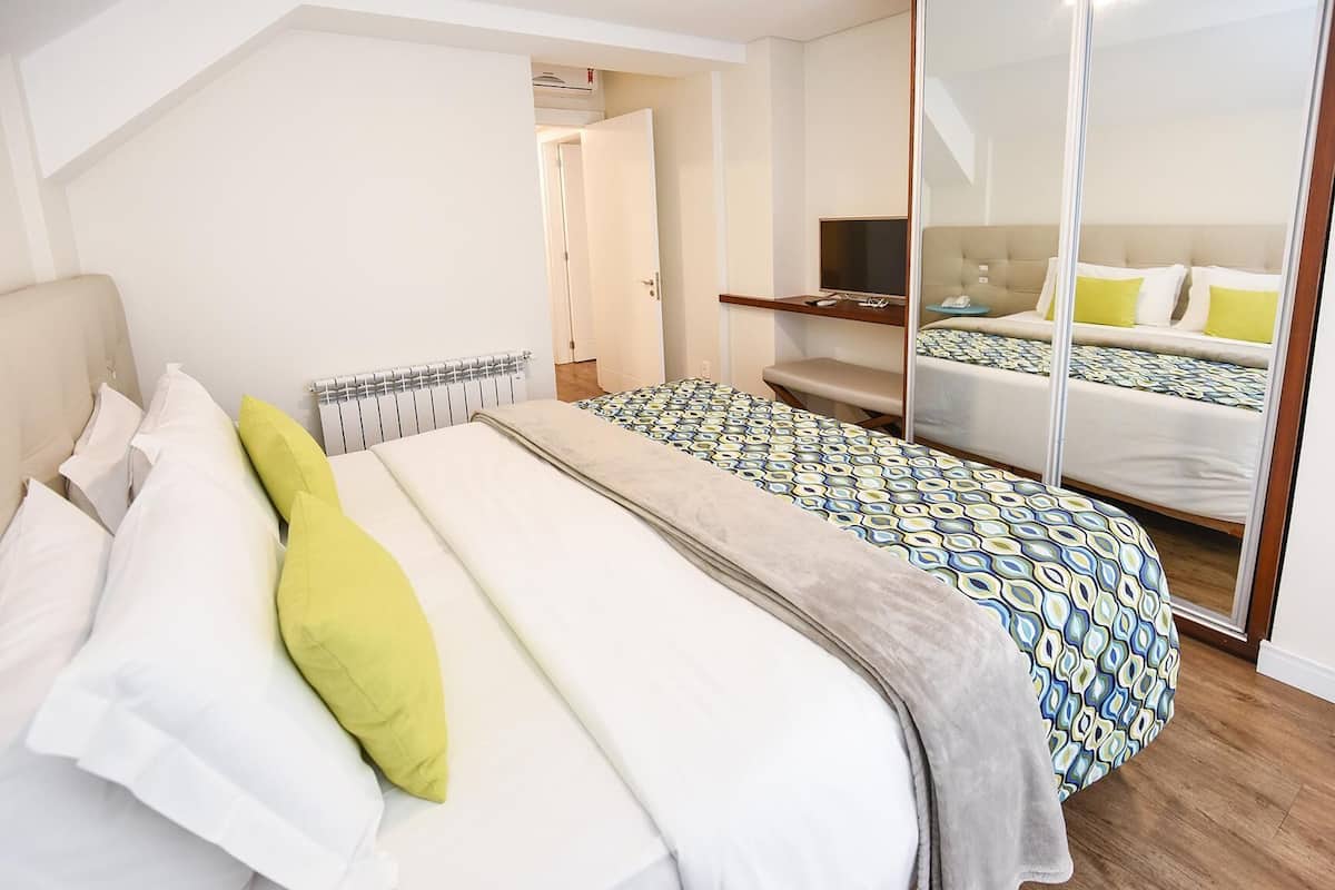 A bedroom with a bed, bedside table, and a mirror.