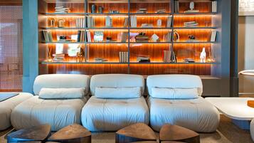 A modern living room with a large sectional sofa, a wooden bookshelf, and a coffee table.