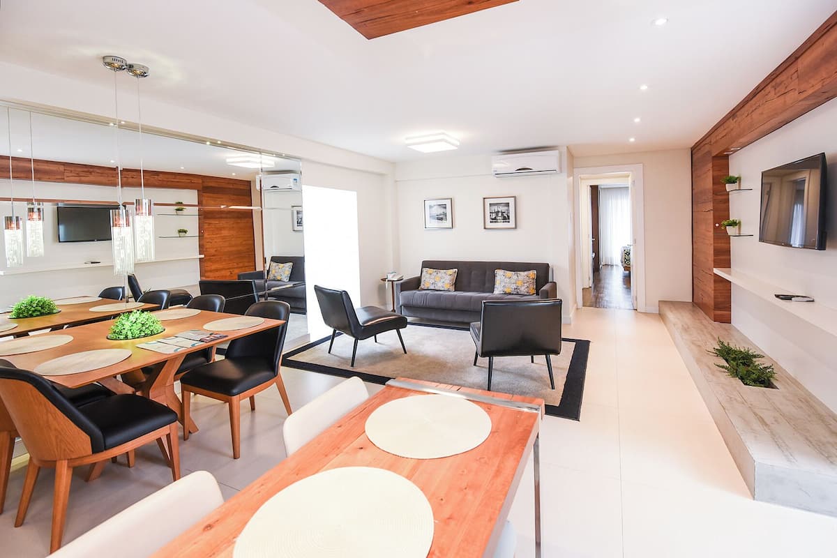 A modern living room with a sofa, coffee table, and dining area with chairs and a table.