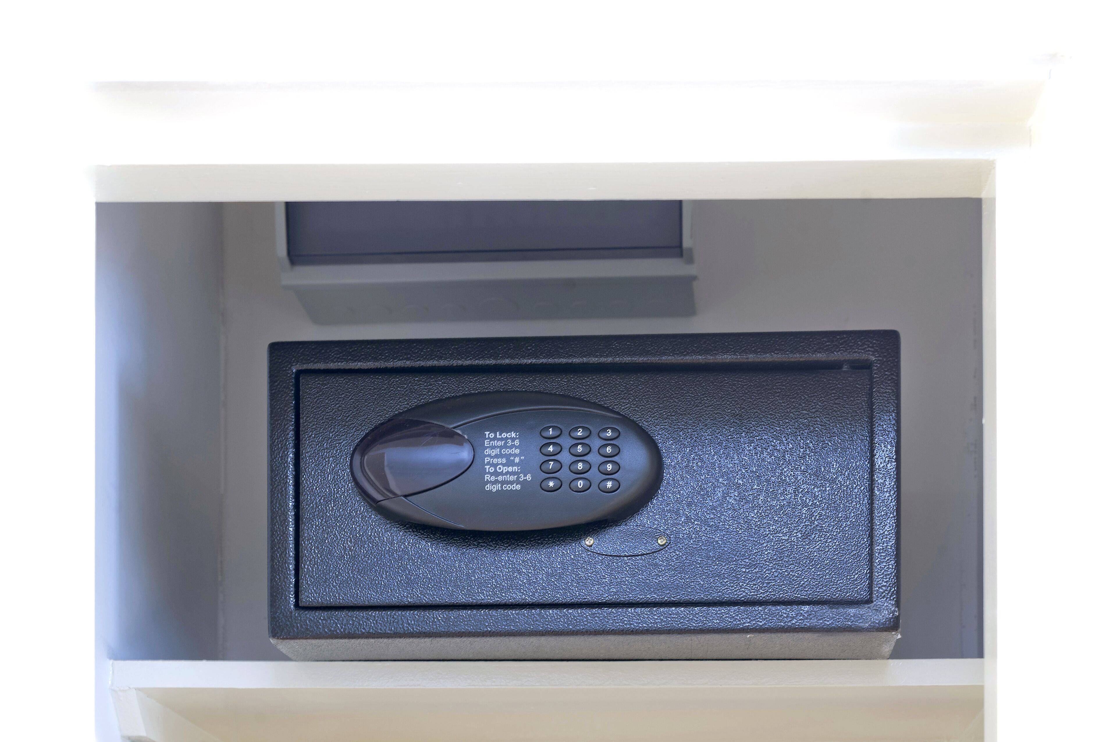 A black remote control inside a white drawer with a textured surface.