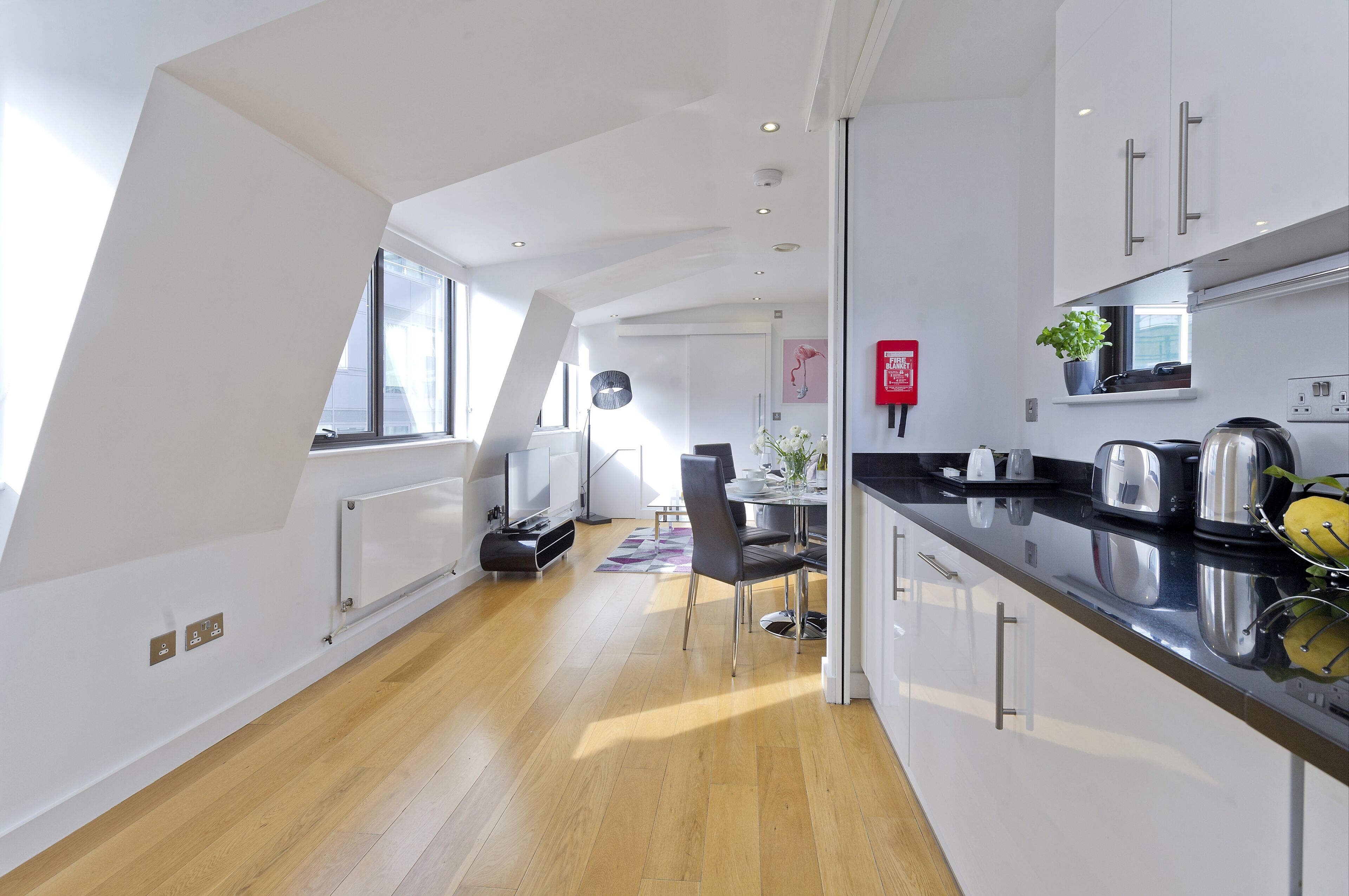 A modern kitchen with a black countertop, stainless steel appliances, and a window.