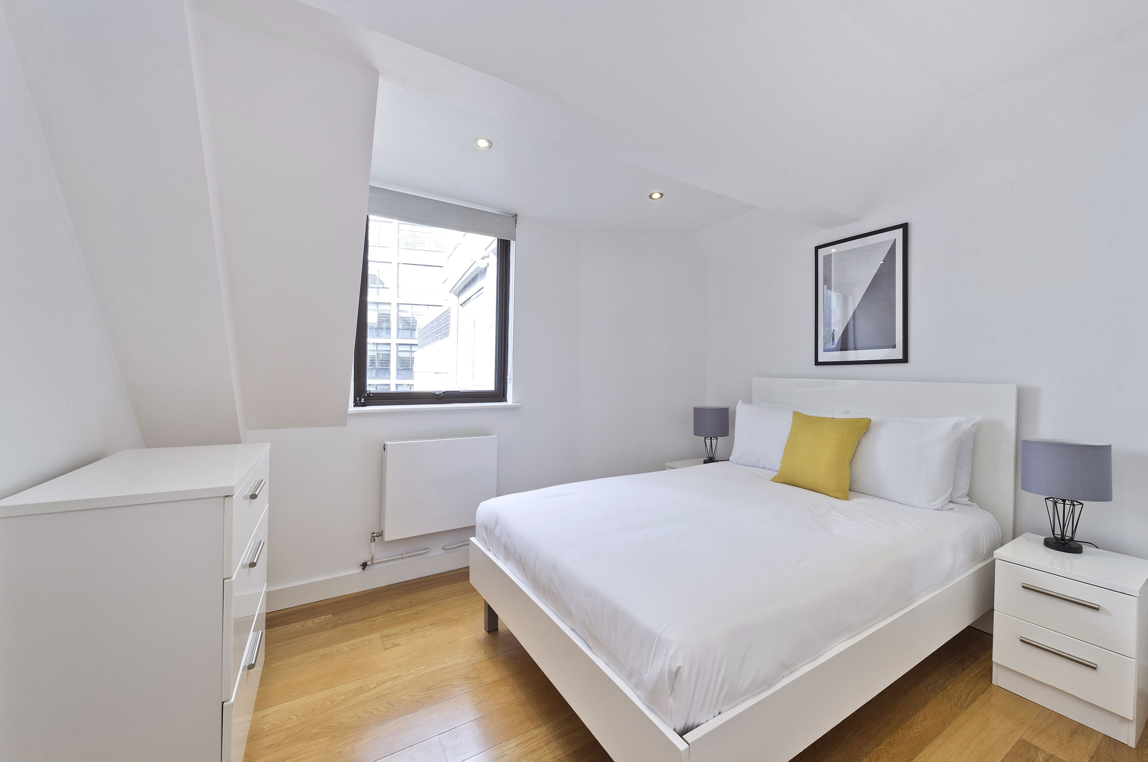 Una camera da letto moderna con un letto grande, comodini, una finestra e un termosifone.