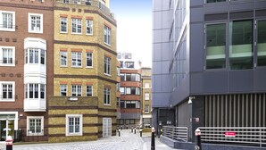 A street view with a mix of traditional and modern buildings, including a corner building with a bay window and a modern glass facade. - Red Lion Court by City2Stay (London)