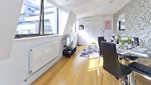 A modern dining area with a high ceiling, large windows, and a view of a building outside. - Red Lion Court by City2Stay (London)