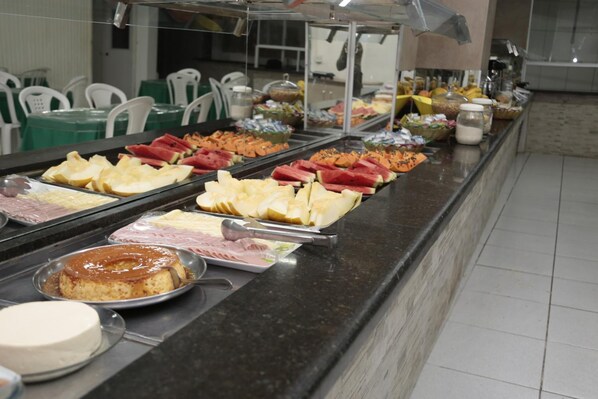 A buffet with various food items including fruits, cheeses, and desserts.
