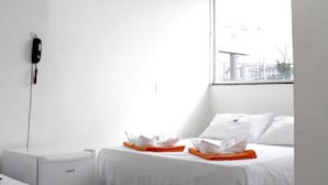 Ein Hotelzimmer mit zwei Betten, einem Fenster mit Aussicht, einem Telefon an der Wand und einem Tisch mit Tablett.