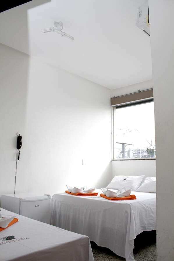 Een hotelkamer met twee bedden, een raam met uitzicht, een telefoon aan de muur en een tafel met dienblad.