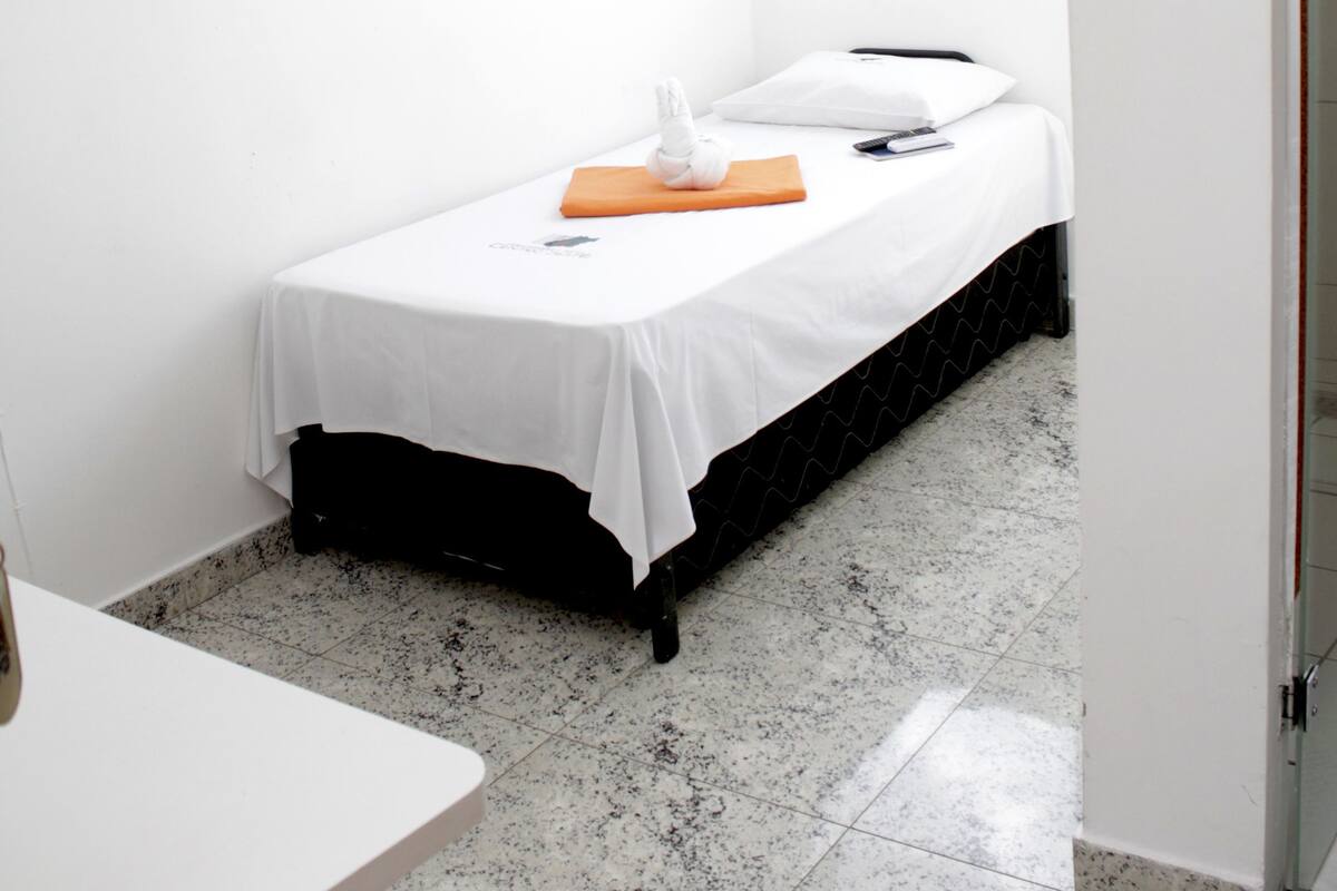 A small, clean room with a single bed, a table, and a window with a view.