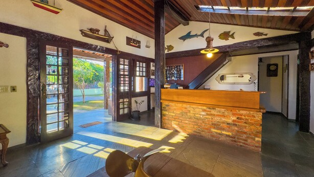 A lobby with a wooden reception desk, a large fan, and a staircase. - Pousada Sonho de Geribá (Búzios)