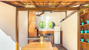 A kitchen with a brick oven, a refrigerator, and a countertop with potted plants. - Pousada Sonho de Geribá (Búzios)
