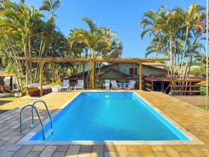 Una piscina al aire libre, sillones reclinables de piscina