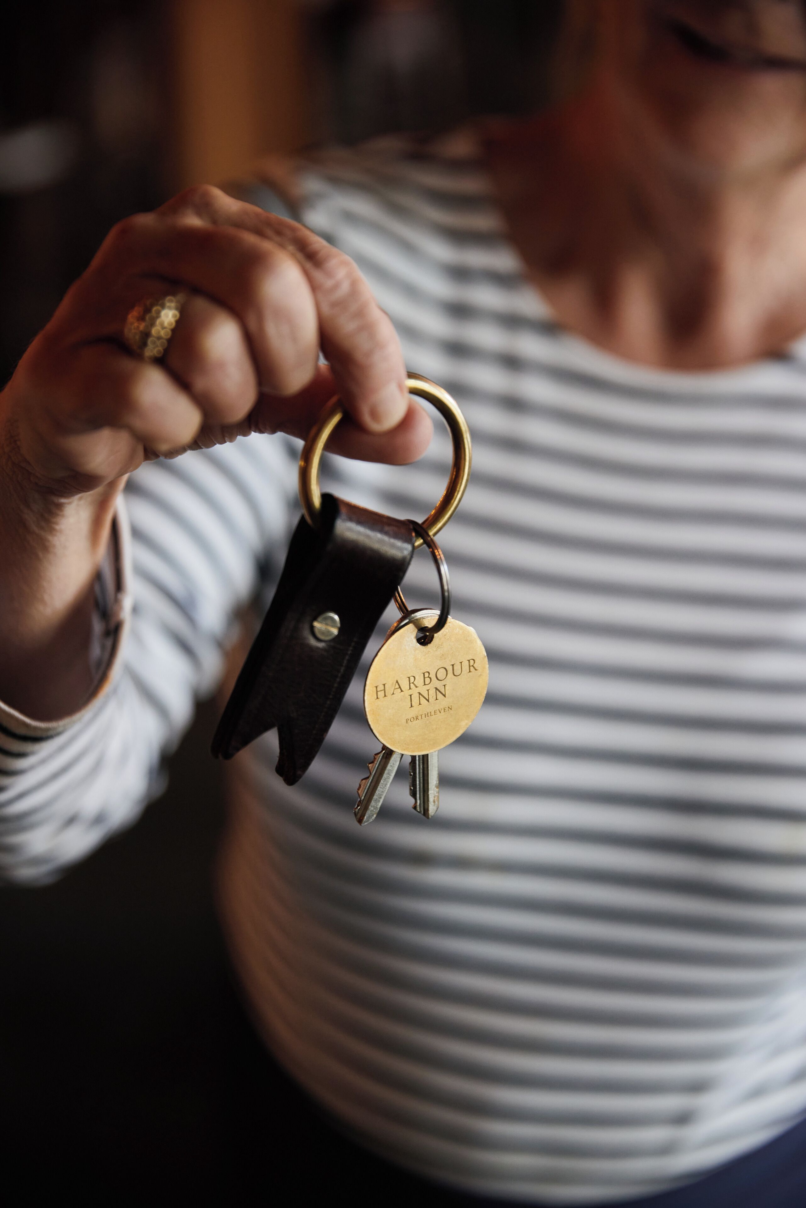 A person holding a set of keys with a keychain labeled 'Harbour Inn'.