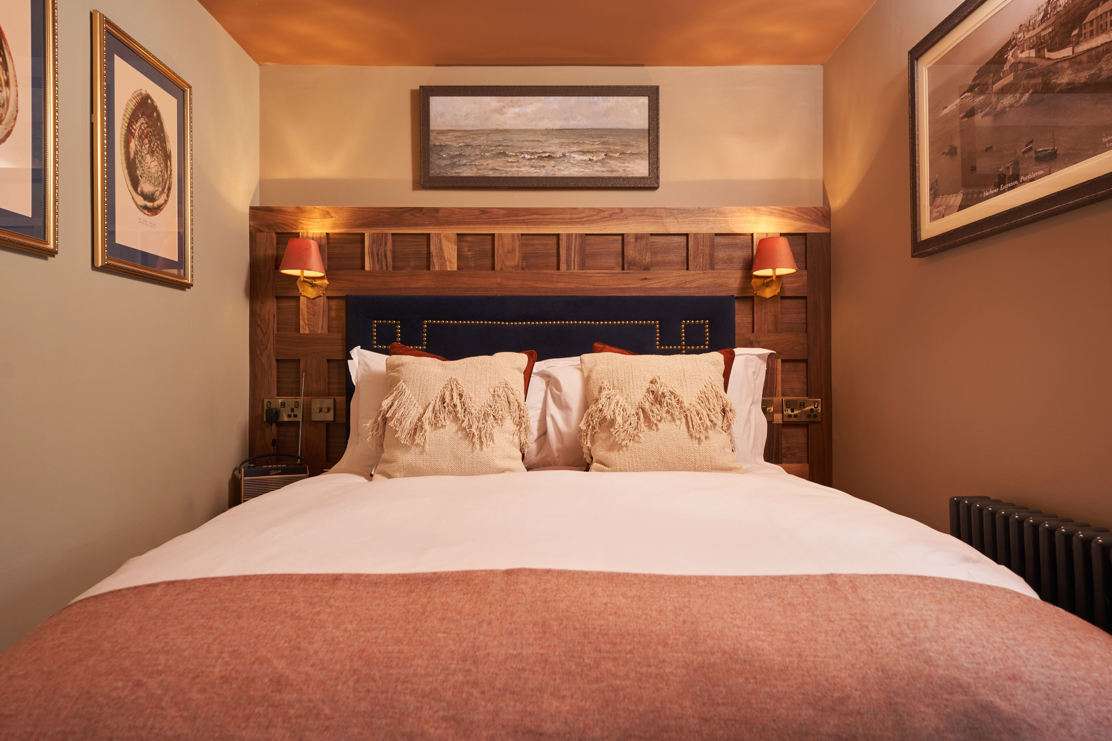 A neatly made bed with a wooden headboard, two bedside lamps, and framed artwork on the walls.