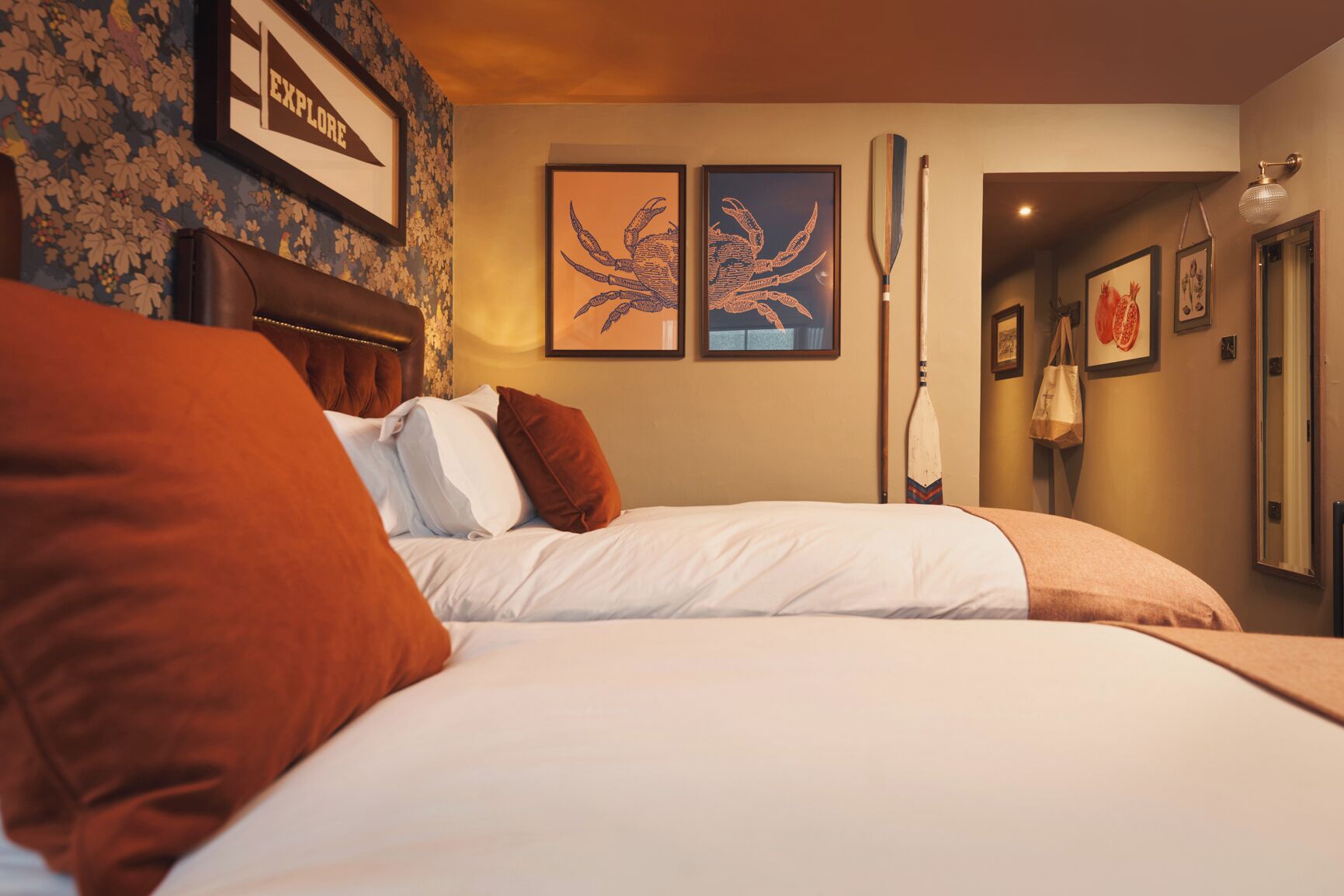 Een hotelkamer met twee bedden, een hoofdeinde, kunstwerken in lijsten en een potplant.