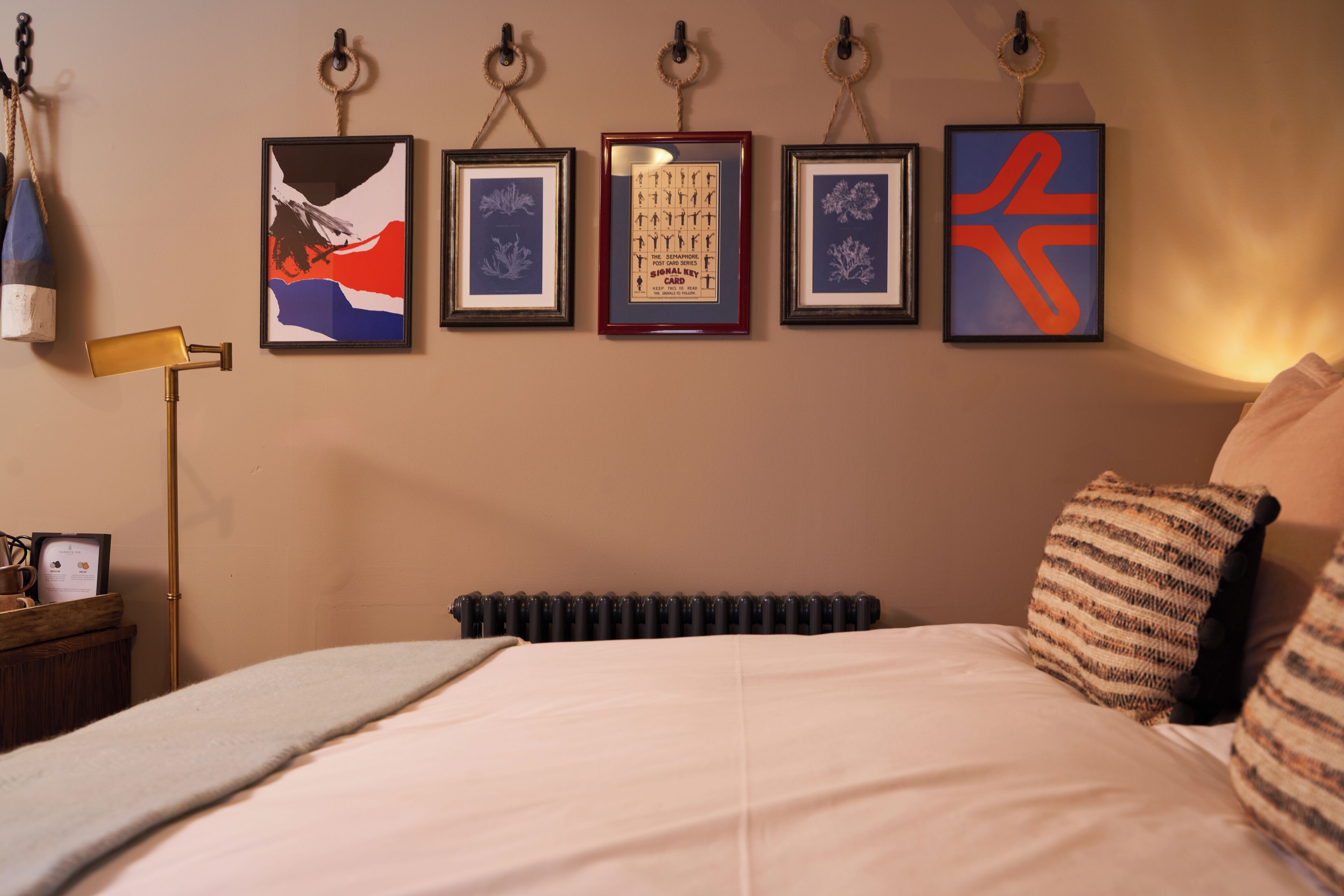 Quarto com cama, radiador e quatro quadros na parede.