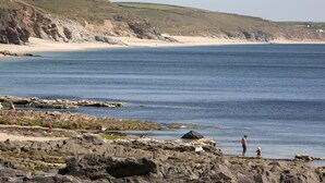 A coastal landscape with rocky terrain and a sandy beach.