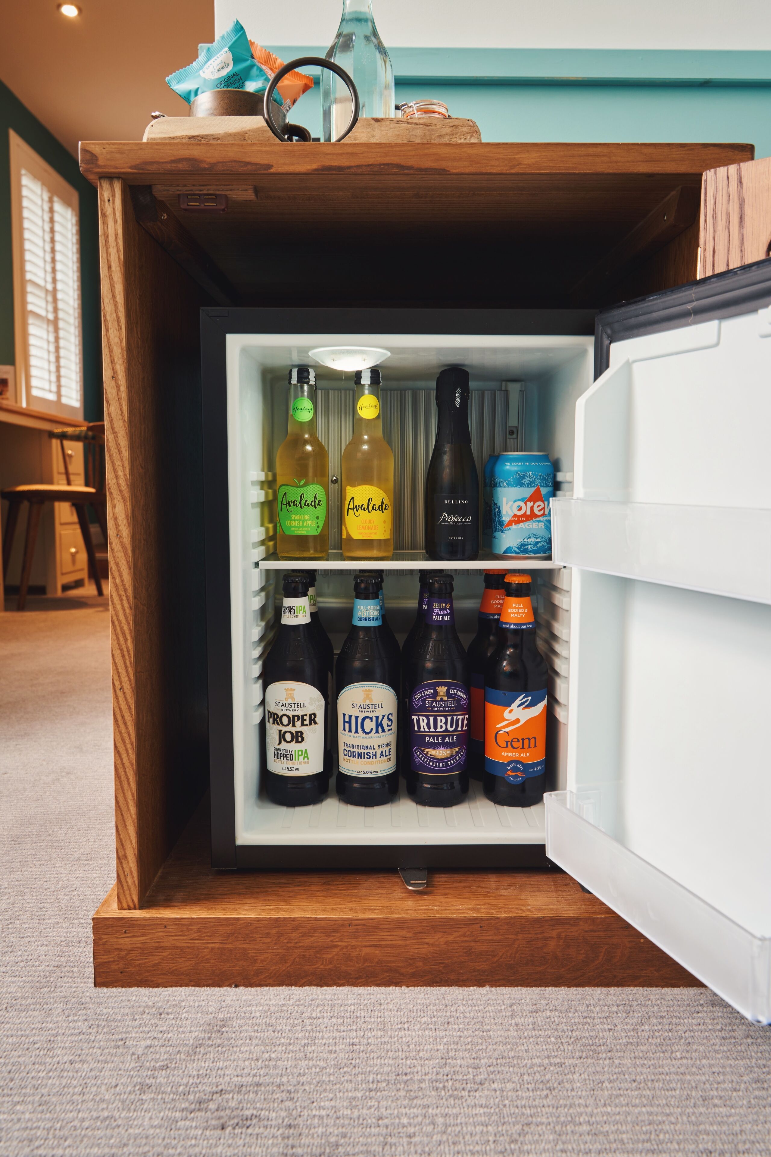 A mini-fridge stocked with various beverages including beers and ales.