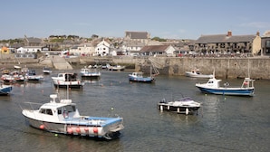 A harbor with various boats docked, a stone wall, and buildings in the background.