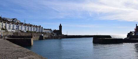 A waterfront promenade with stone piers, a historic tower, and terraced houses.