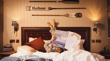 A person lying on a bed with a map, a wooden paddleboard with 'Harbour' written on it, and a headboard with a map of a coastal area.