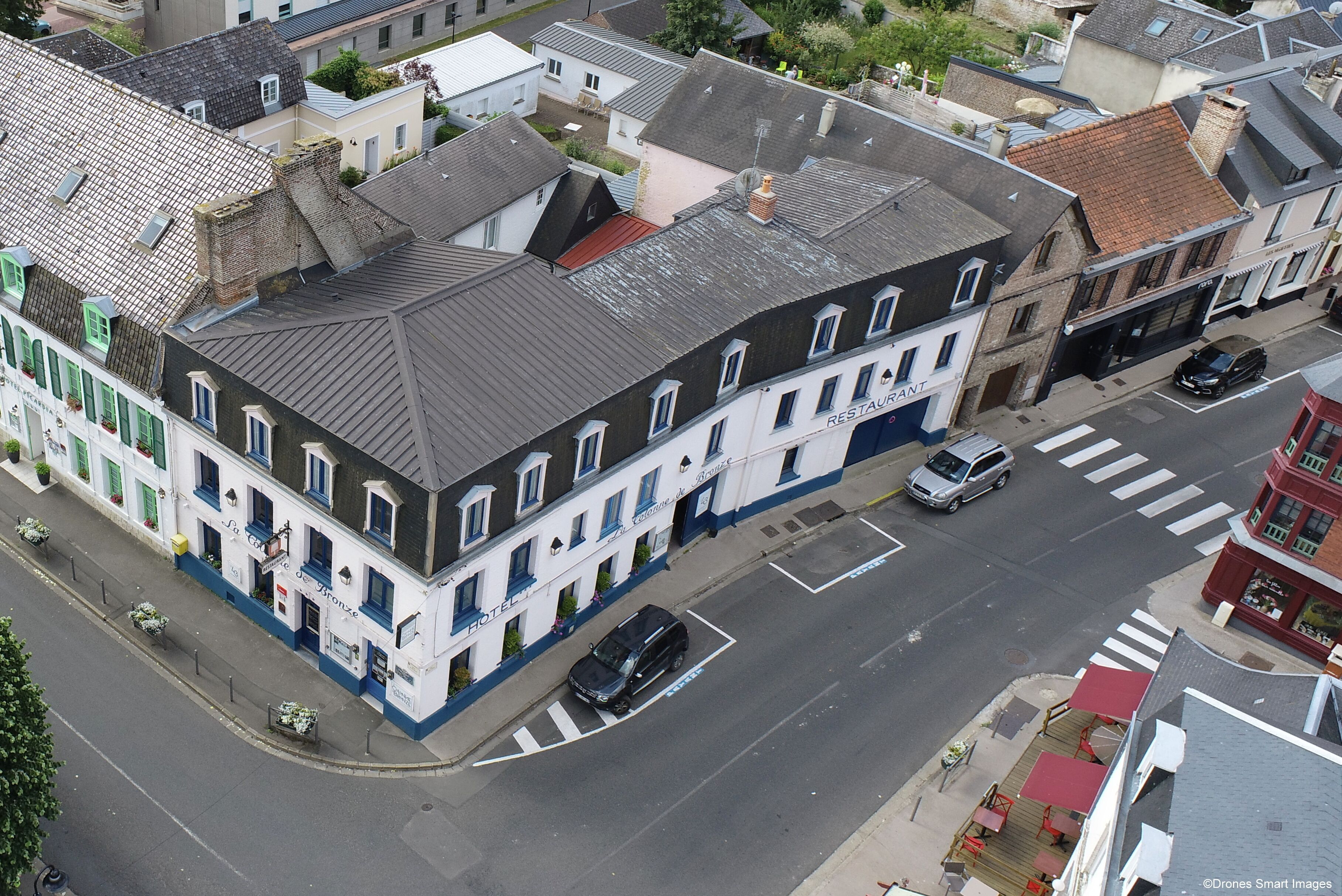 Un hotel de estilo arquitectónico europeo clásico, que presenta un edificio prominente en esquina con techo de tejas y un letrero de restaurante visible.
